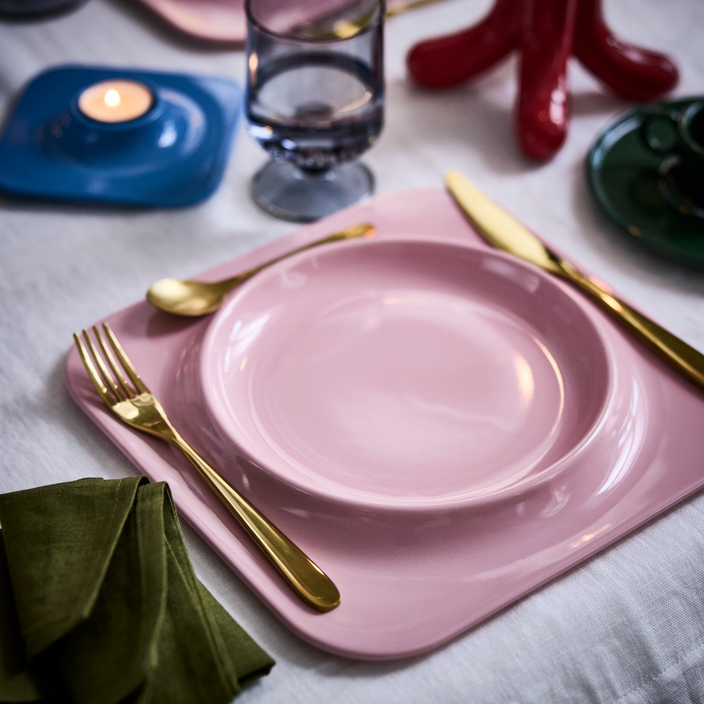 A pink VINTERFINT plate – a design collaboration with Gustaf Westman – is on a festively decorated dinner table.