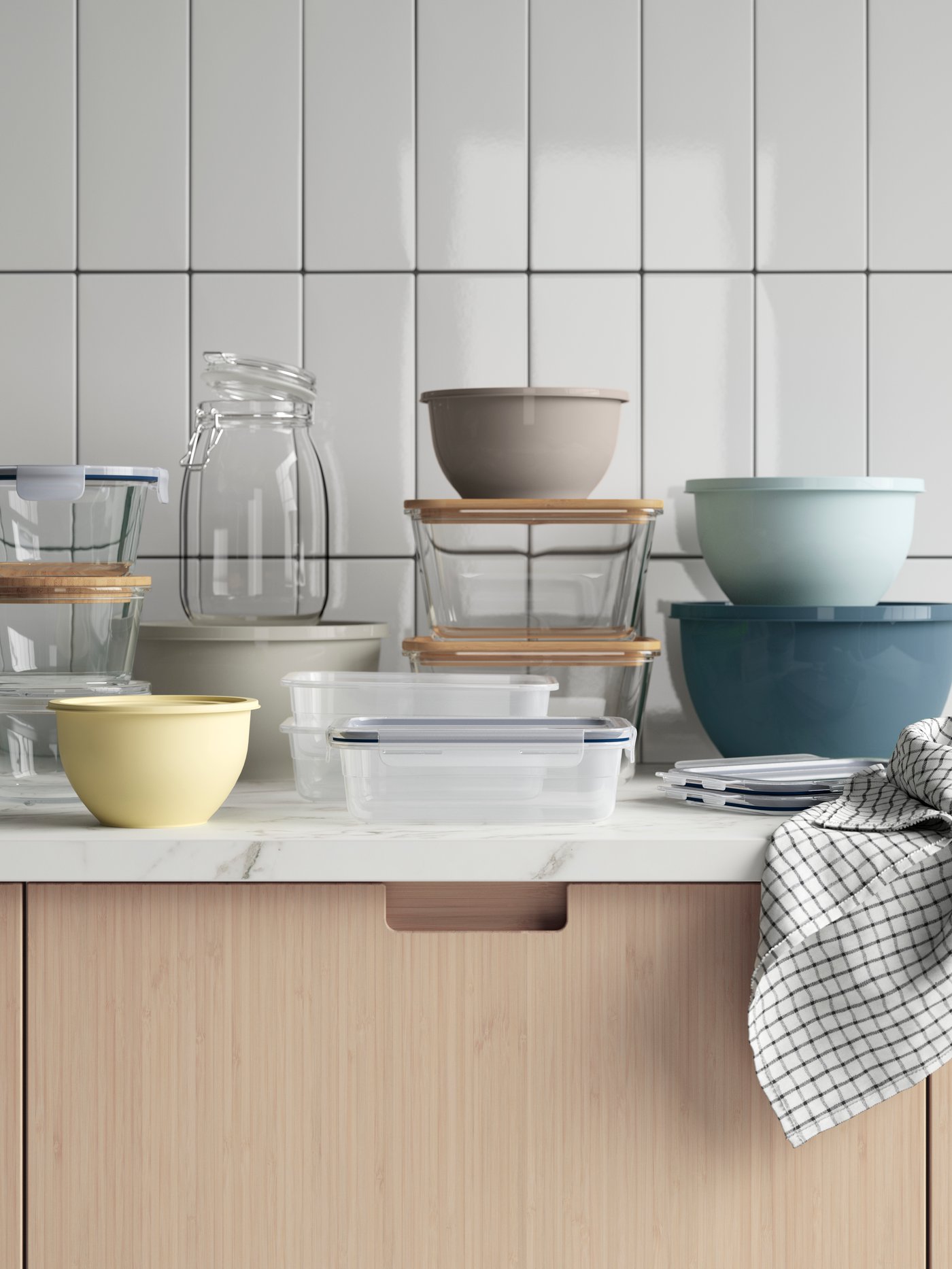 Several food storage containers of different types are stacked on a worktop, including colourful GARNITYREN bowls with lids.